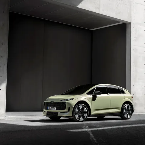 Elettronauti - Audi A2 e-tron verde chiaro vista di lato davanti a un edificio in cemento