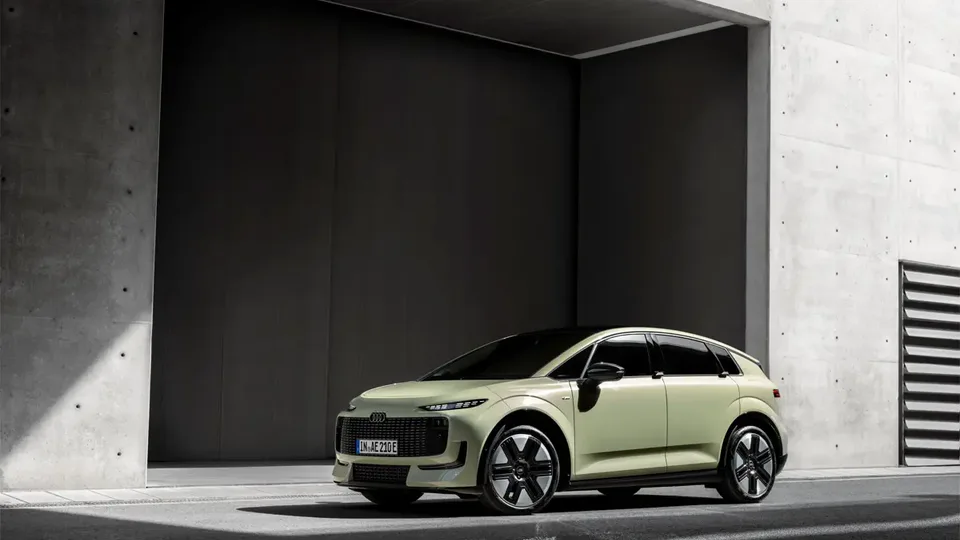 Elettronauti - Audi A2 e-tron verde chiaro vista di lato davanti a un edificio in cemento