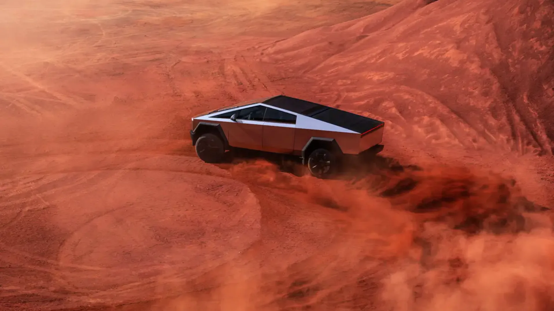 Elettronauti - Tesla Cybertruck argento in vista posteriore di tre quarti tra polvere rossa