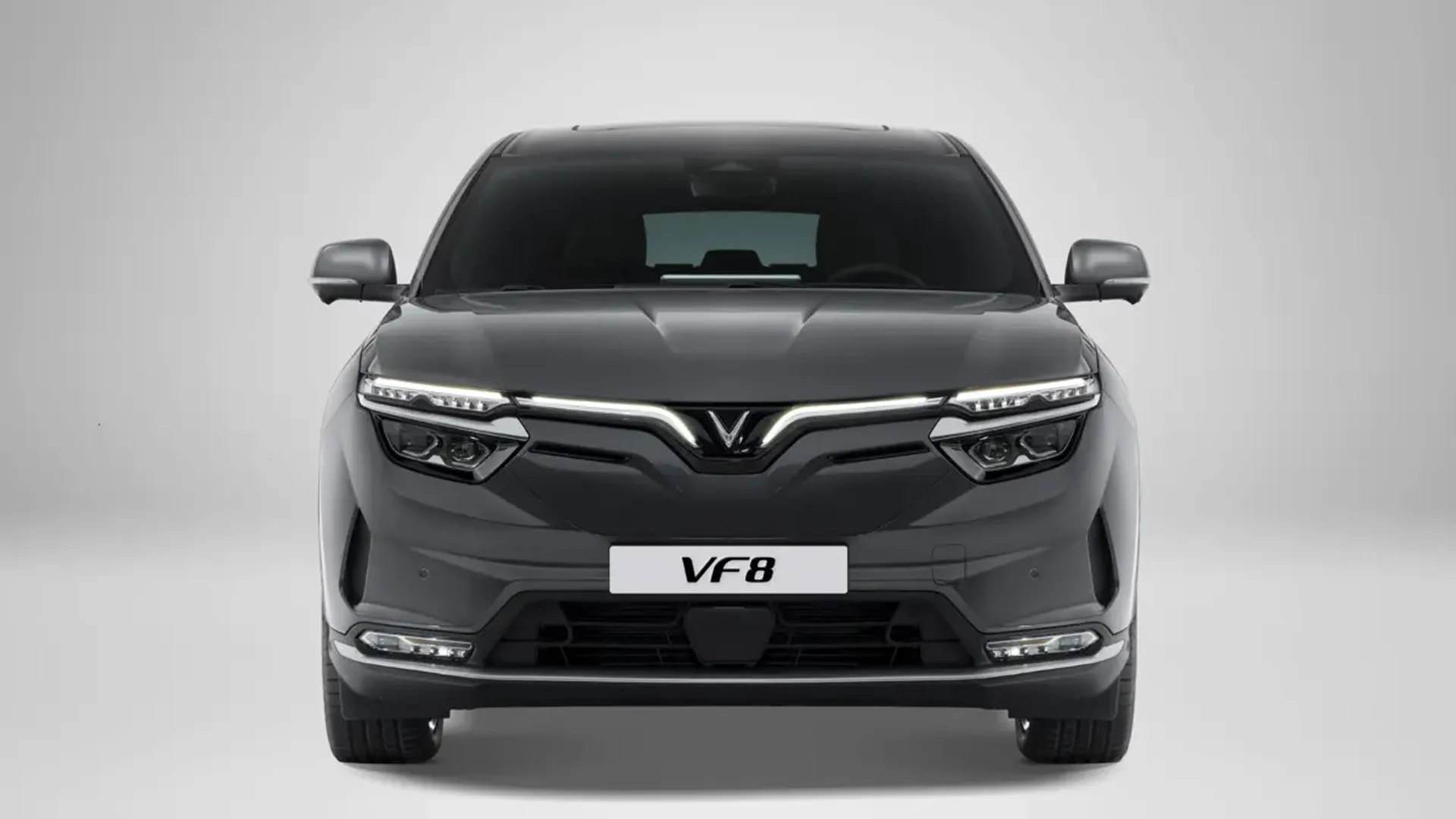 Elettronauti - Vista frontale di una VinFast VF 8 grigio scuro con barra luminosa accesa.