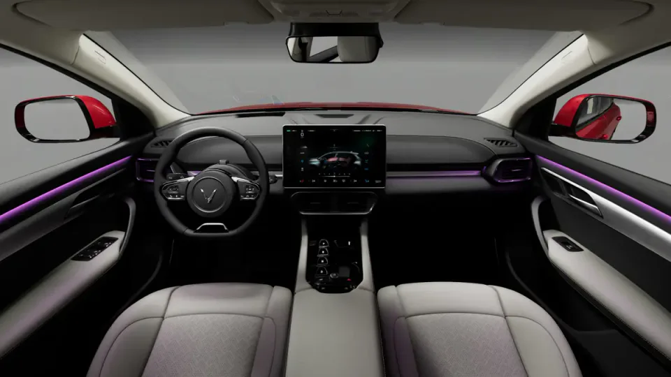 Elettronauti - Abitacolo anteriore della VinFast VF 8 con sedili grigio chiaro, display centrale e illuminazione ambiente viola.